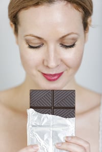 Attractive woman choosing between chocolate and a fresh apple.