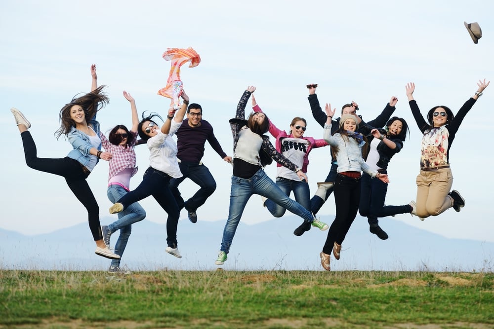 Happy teen girls having good fun time outdoors jumping up in air